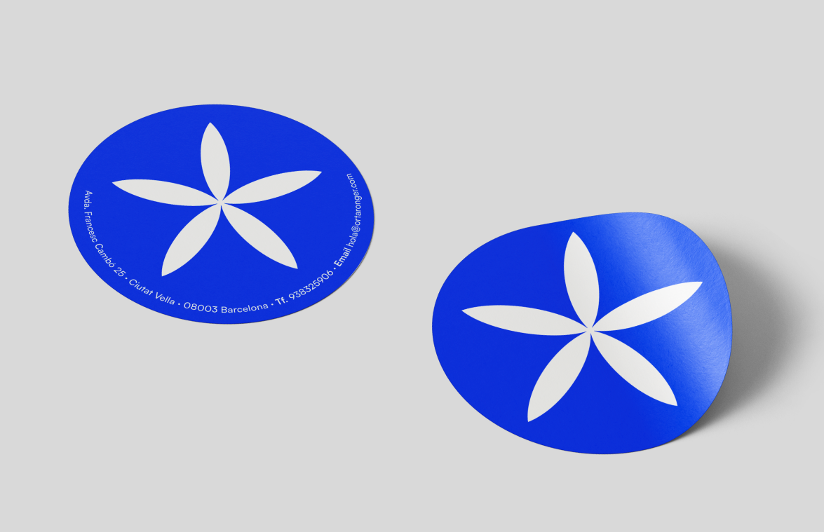 Pegatinas redondas de Or Taronger con el símbolo floral blanco sobre fondo azul eléctrico, utilizadas como elementos de marca y contacto.